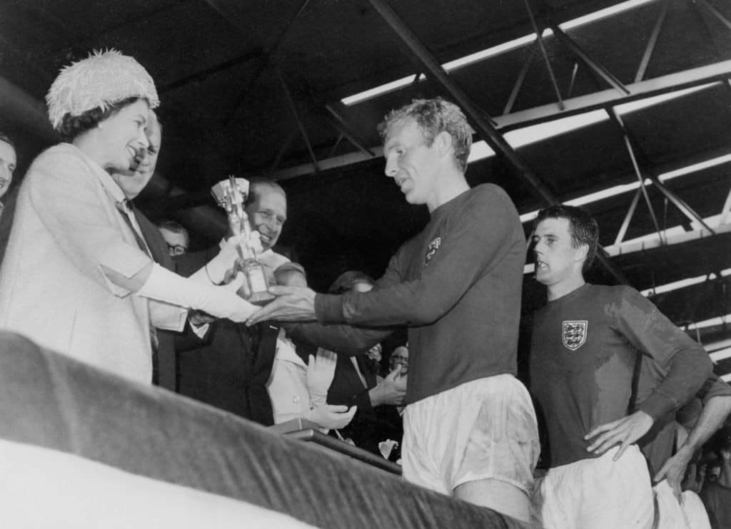 LONDON, UNITED KINGDOM - JULY 30: Queen Elizabeth of England presents the Jules Rimet Cup to Bobby Moore, captain of England's national soccer team, as her husband Prince Philip (C) and forward Geoff Hurst (R) look on after England beat West Germany 4-2 in extra time in the World Cup final 30 July 1966 at Wembley stadium in London. Hurst scored three goals, two of them in extra time, to help England win its first World title. AFP PHOTO (Photo credit should read STAFF/AFP via Getty Images)
